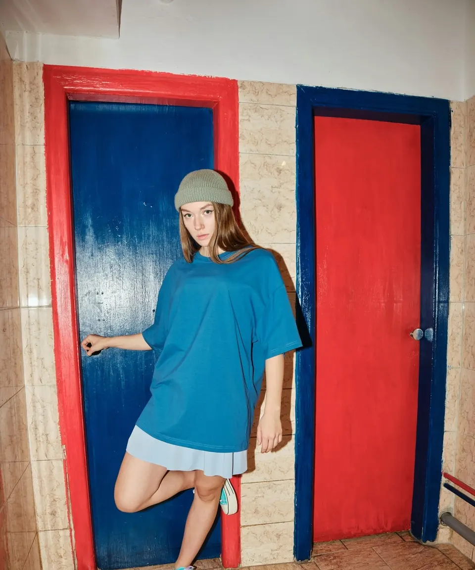 Young woman in a blue shirt leaning against a blue door