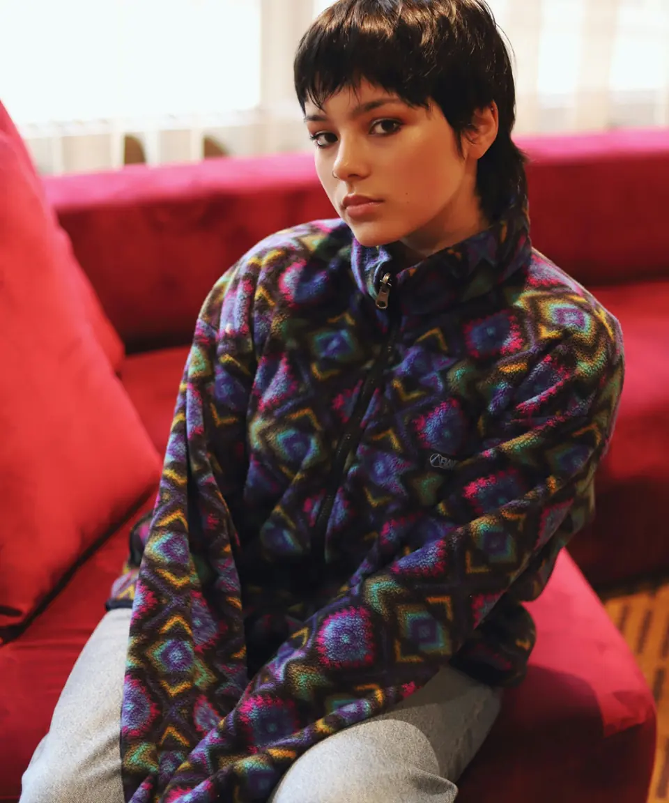 Young flexer in a patterned fleece jacket on a red velvet couch