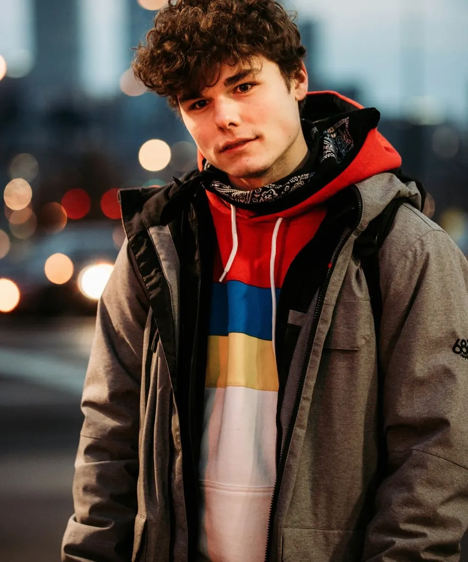 Young man in a winter jacket in the city at dusk