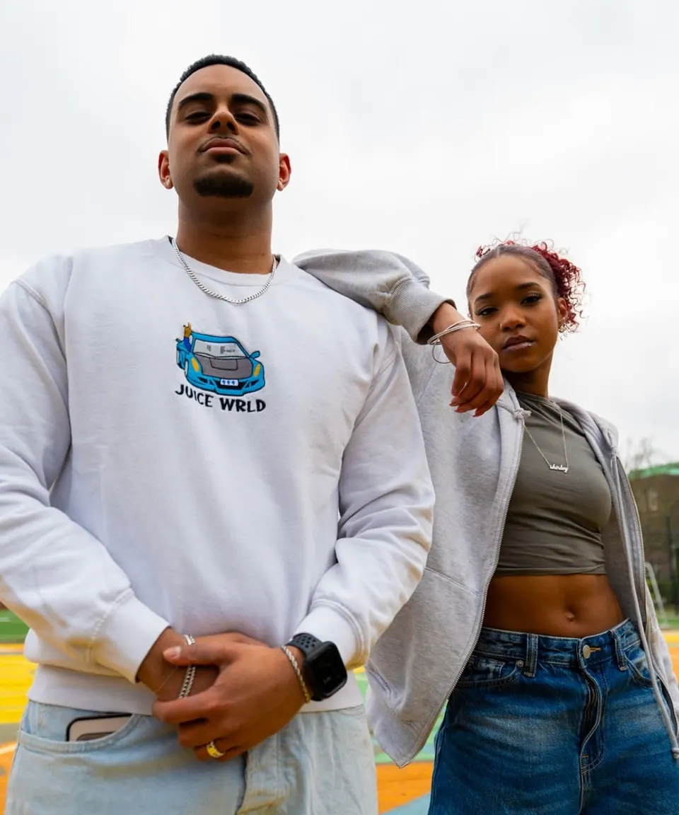 Two young people posing outdoors by a city sports court
